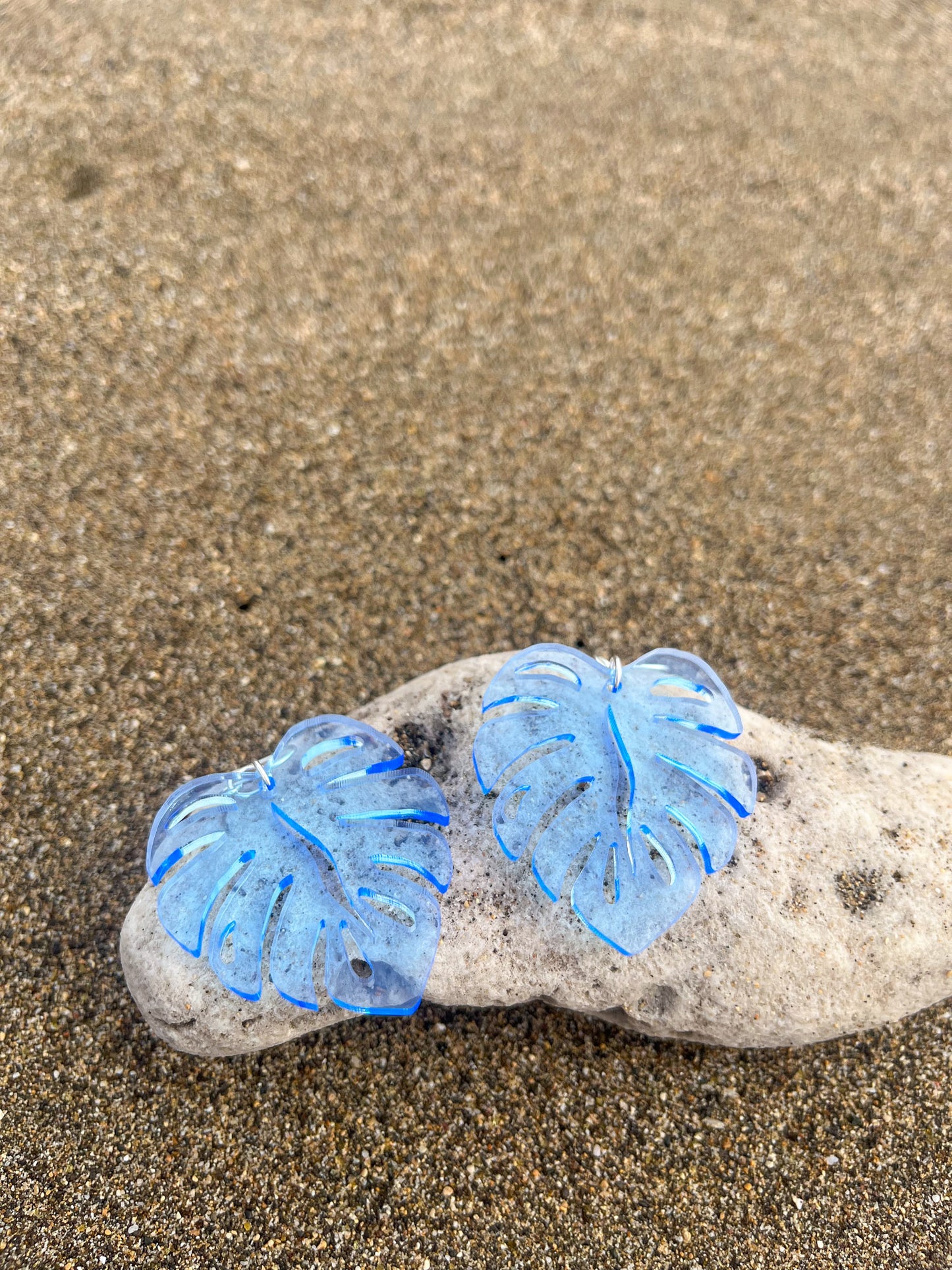 Blue Acrylic Earrings in the shape of a Monstera leaf. Approximately 1.5" x 1.6"