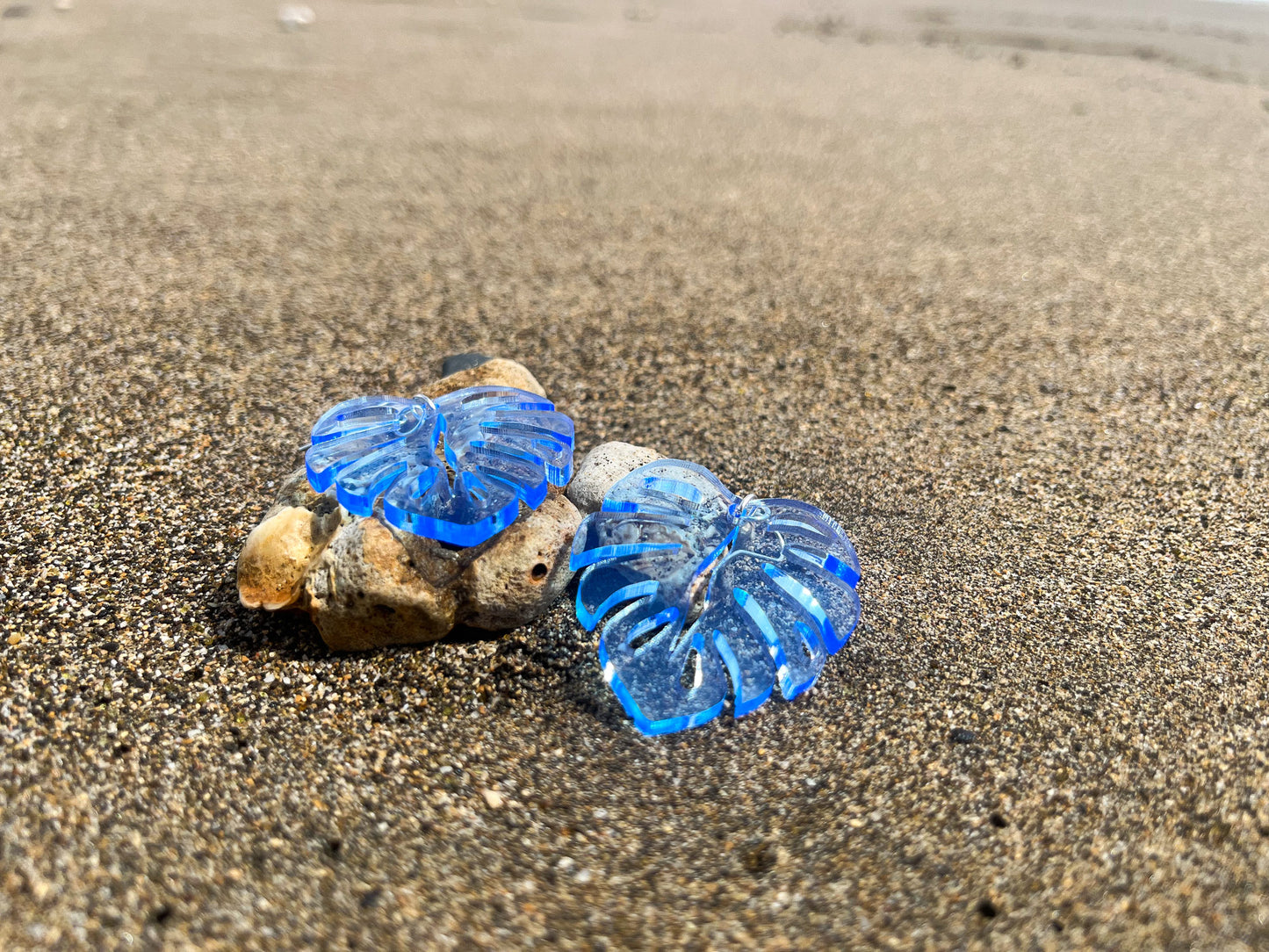 Blue Acrylic Earrings in the shape of a Monstera leaf. Approximately 1.5" x 1.6"