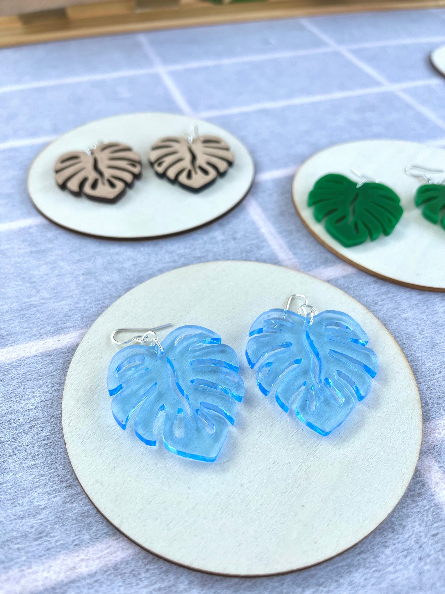 Blue Acrylic Earrings in the shape of a Monstera leaf. Approximately 1.5" x 1.6"