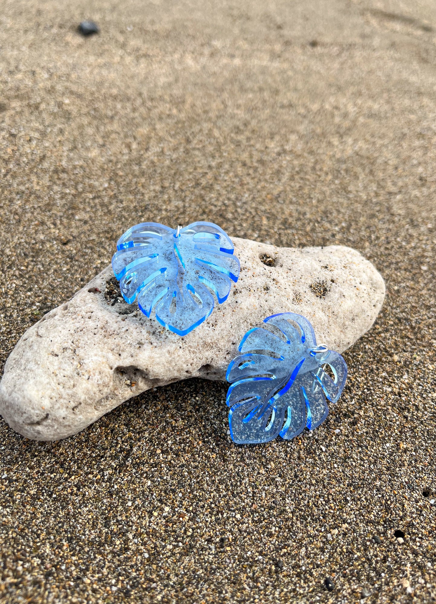 Blue Acrylic Earrings in the shape of a Monstera leaf. Approximately 1.5" x 1.6"