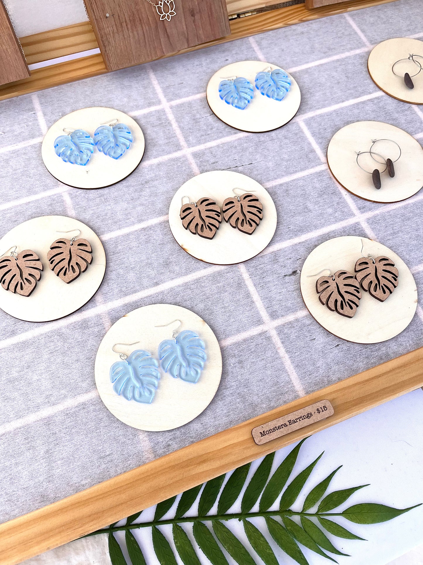 Aerial view of Monstera earrings, both wooden and blue acrylic.