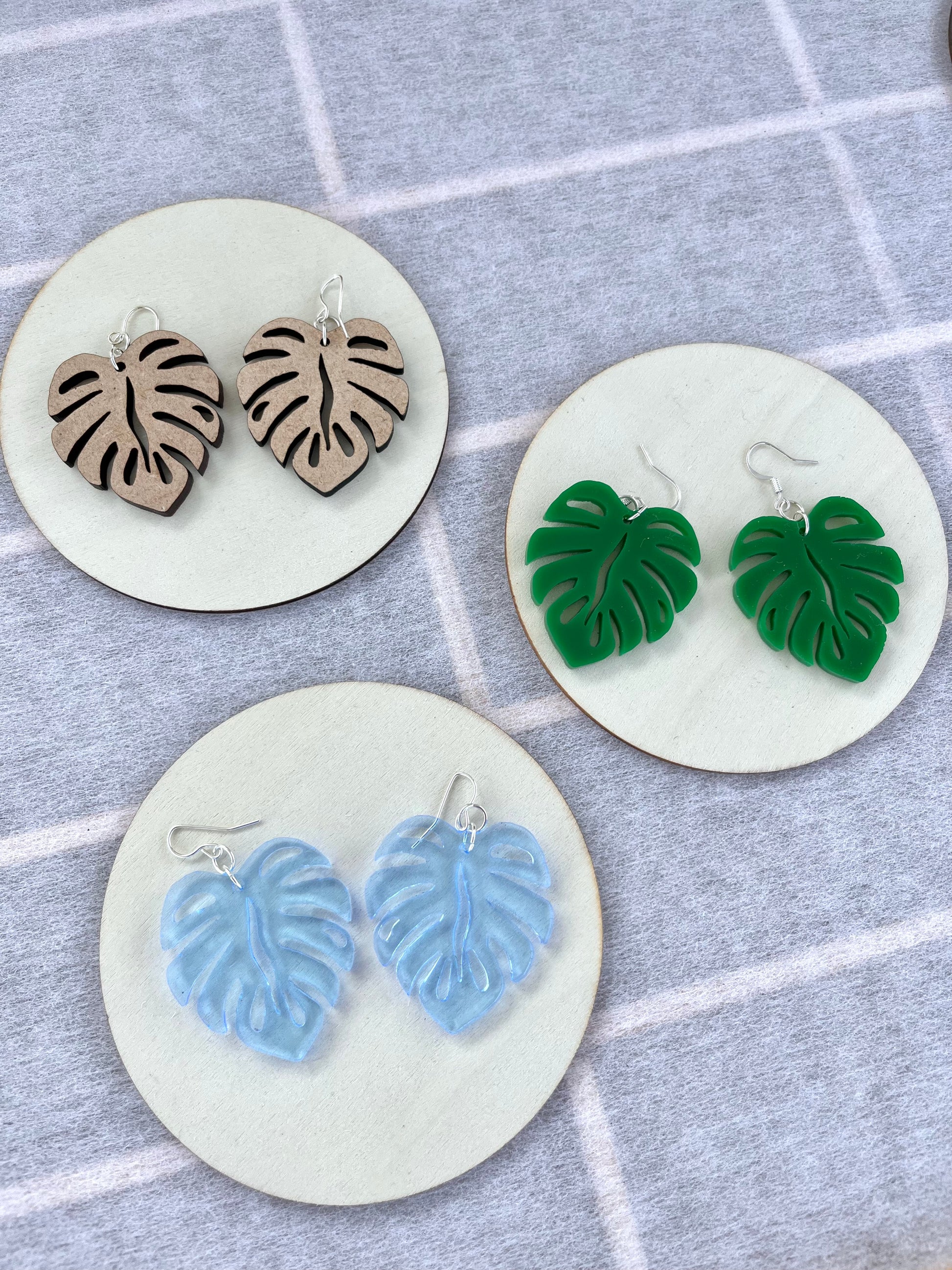 Blue Acrylic Earrings in the shape of a Monstera leaf. Approximately 1.5" x 1.6"